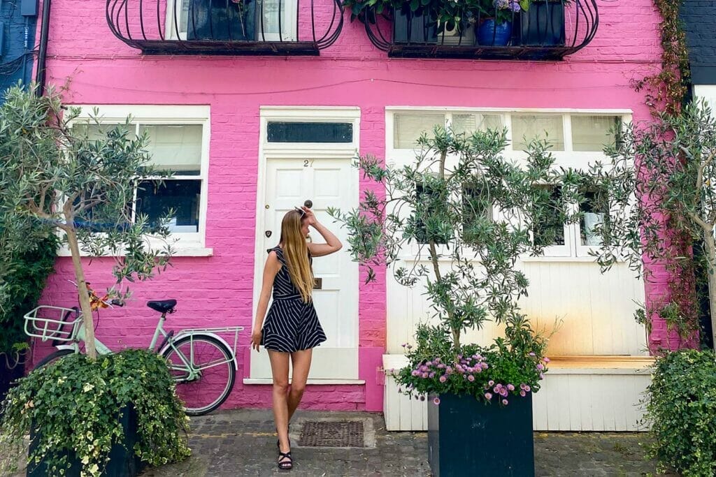 woman-standing-in-front-of-pink-house-in-london-in-summer-time